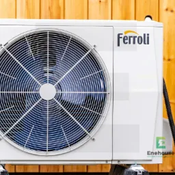 Biała pompa ciepła Ferroli na tle drewnianej ściany. Widoczny wentylator i logo Enehouse. Ujęcie z boku, podkreślające nowoczesny design i energooszczędność urządzenia.