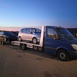 Euro Cars - Niebieska laweta Mercedes-Benz z dwoma samochodami (Audi A3 i Honda Jazz) na platformie, sfotografowana o zmierzchu.