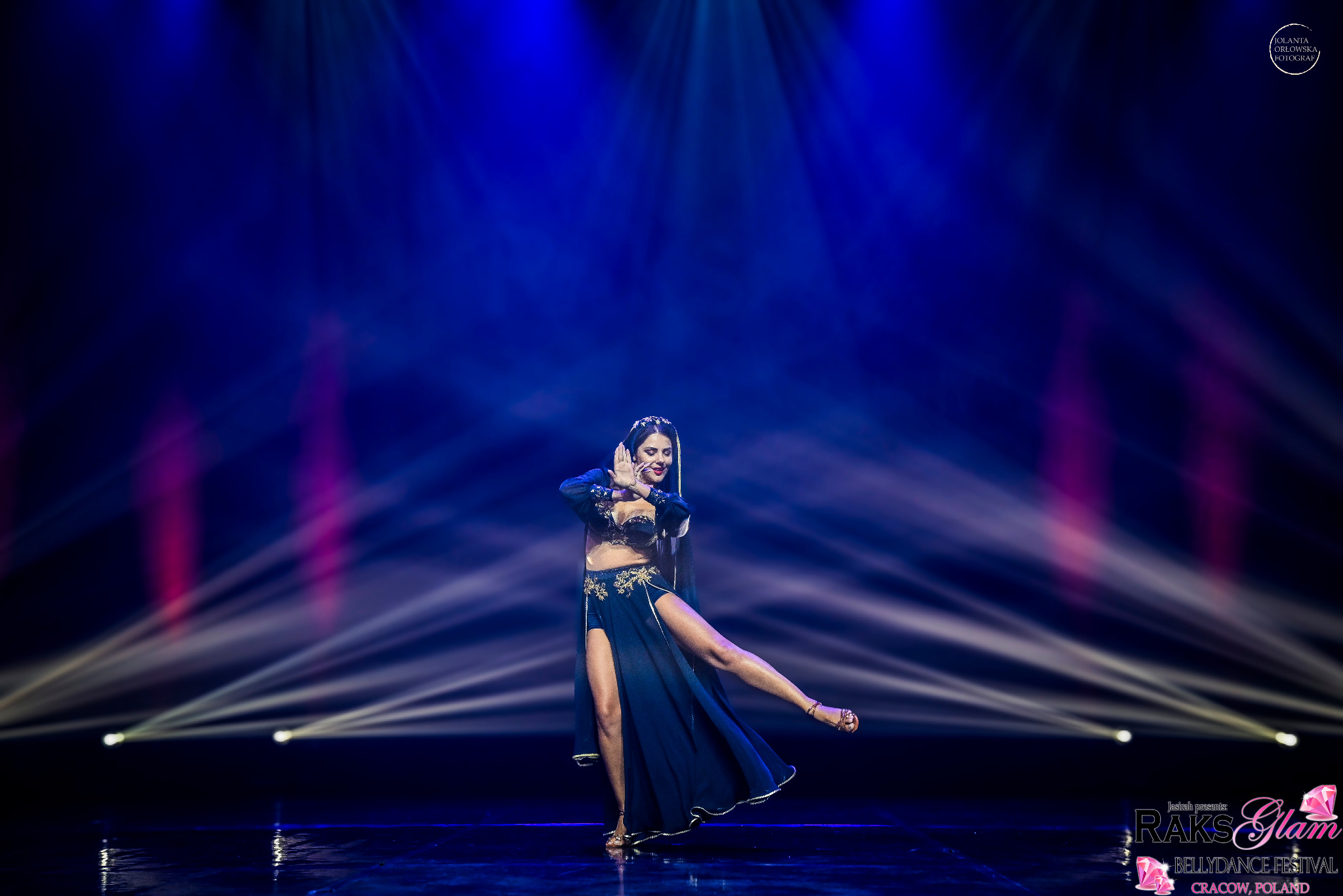 Tancerka w kostiumie belly dance na scenie w niebieskim oświetleniu, podczas festiwalu tańca.