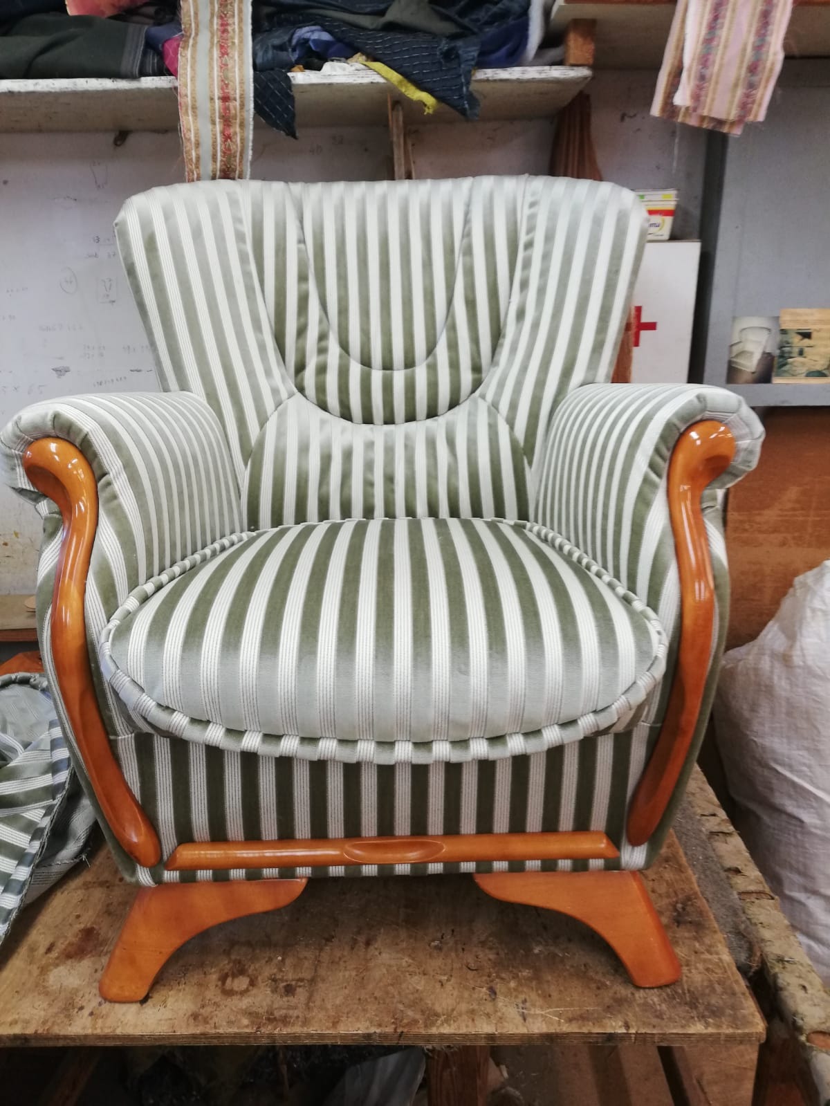 Fotel po renowacji w paski z drewnianymi elementami, wykonany przez zakład w Poznaniu. Widoczne detale wykończenia i nowe obicie.
