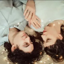 Para leżąca na kocu, otoczona światełkami, kobieta z pierścionkiem na palcu.