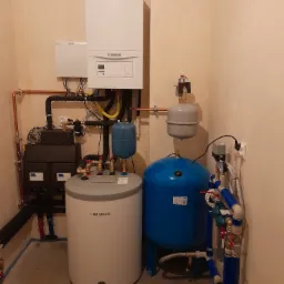 Instalacja kotła gazowego Vaillant, zbiornika Biawar i pompy Aquasystem w kotłowni z beżowymi ścianami.