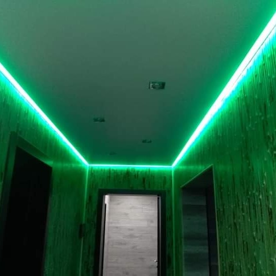 Korytarz z zielonym oświetleniem LED zamontowanym pod sufitem, ściany pokryte tapetą z motywem bambusa.