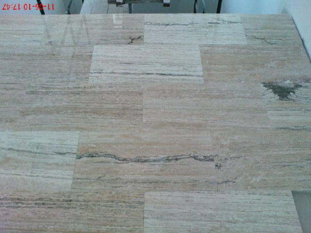 Położona, beżowa podłoga z płytek imitujących drewno, widok z góry, fuga w kolorze płytek, częściowo widoczny statyw malarski w tle.