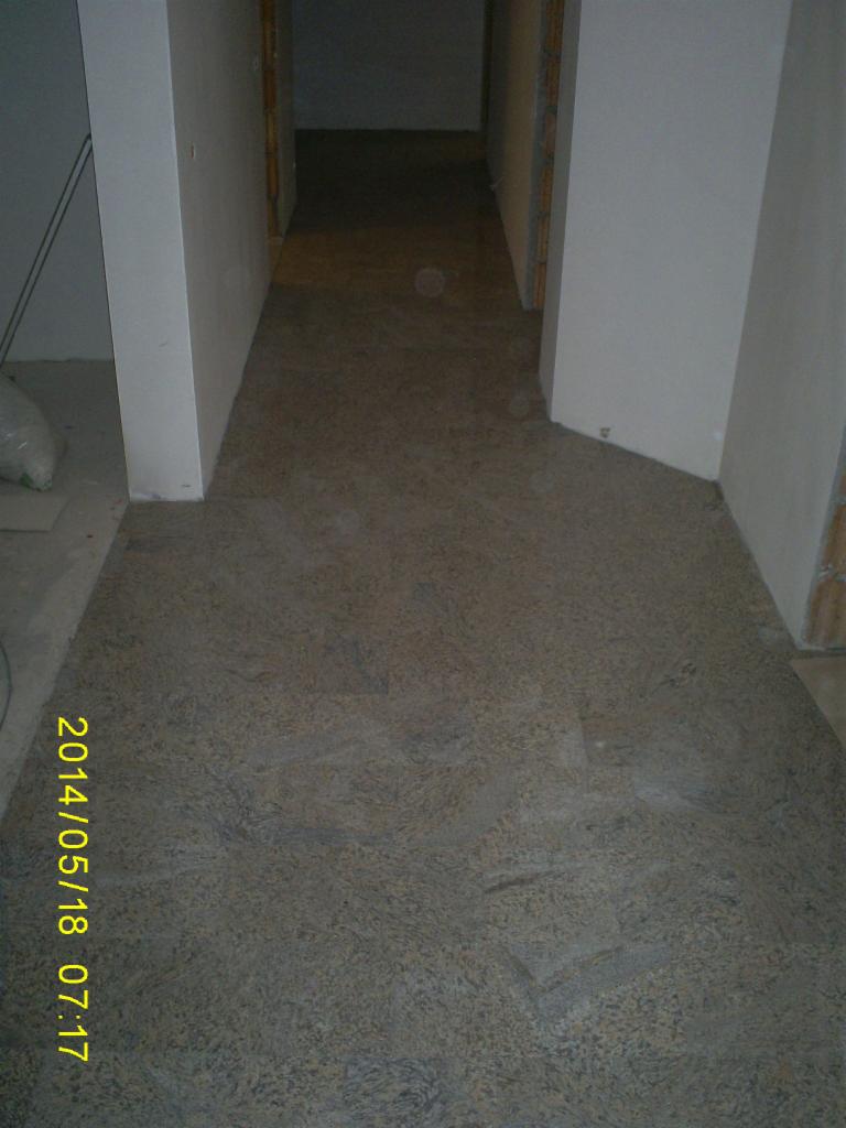 Wykończona podłoga z płytkami o nieregularnym wzorze w korytarzu. Widoczne białe ściany i fragmenty futryn. Na podłodze widoczny odcisk daty.