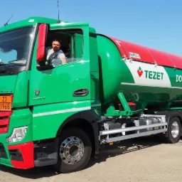 Zielono-czerwona cysterna Mercedes z napisem 'TEZET Dostawy Gazu', kierowca w kabinie, tablica ostrzegawcza z numerem 23 i 1965.