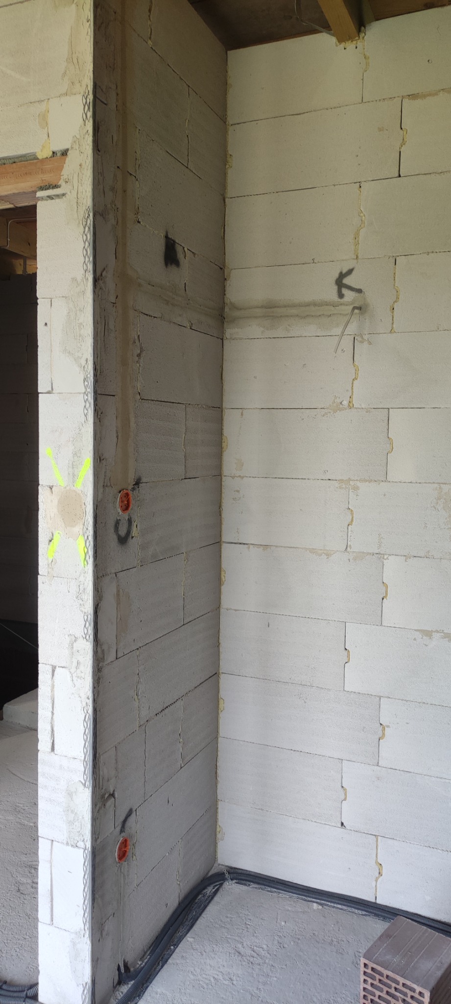 Surowy stan instalacji elektrycznej w budynku z betonu komórkowego w Nowym Sączu, widoczne peszle z przewodami, puszki instalacyjne i oznaczenia na ścianach.