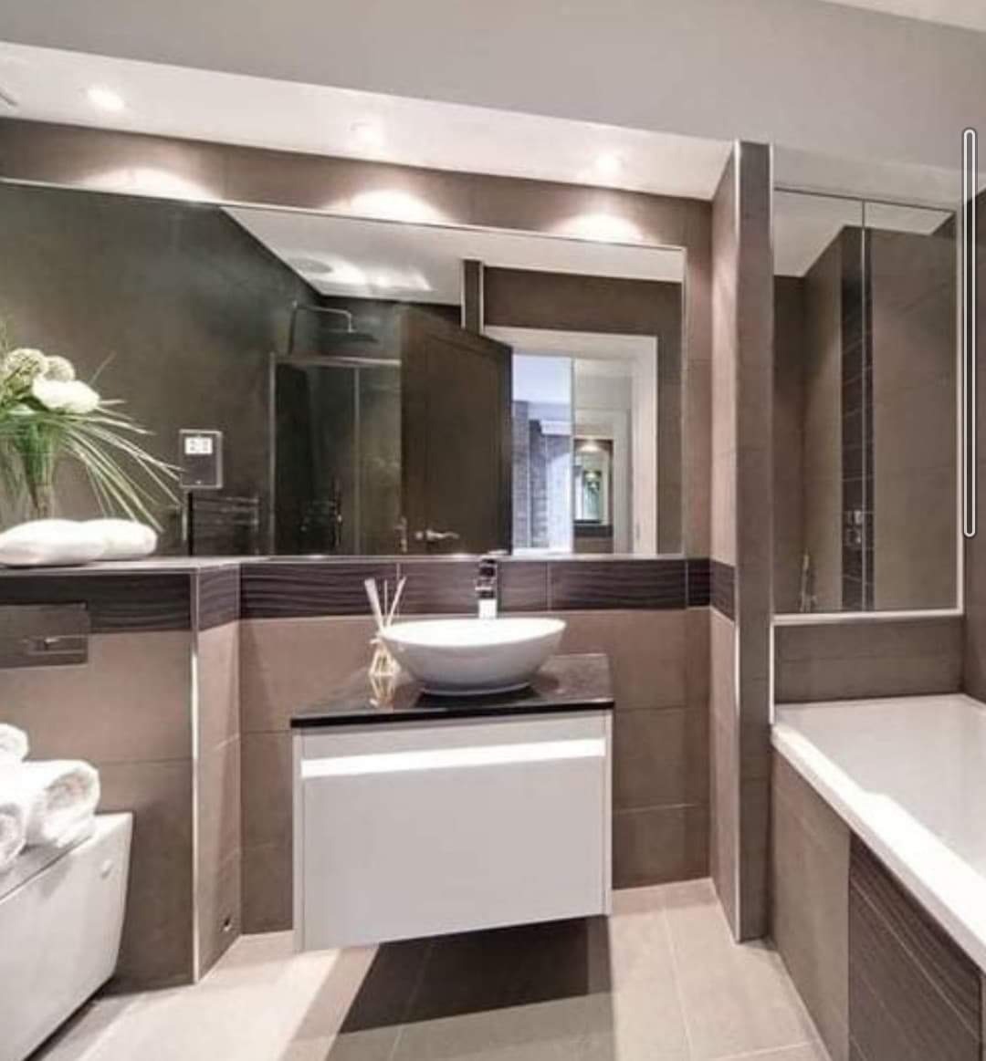 Nowoczesna łazienka z dużym lustrem, umywalką nablatową na szafce z czarnym blatem, widoczną kabiną prysznicową i wanną.