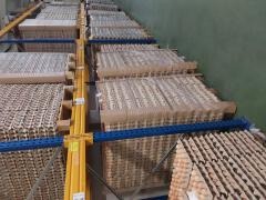 Palety z tekturowymi wytłaczankami jaj na metalowych regałach magazynowych, widok z dołu, oświetlenie magazynowe.