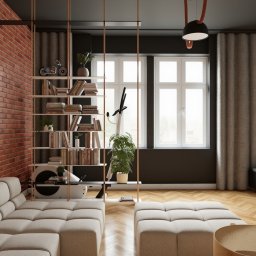 Hektar Studio Projektowe - Nowoczesny salon z ceglaną ścianą, beżową sofą modułową, drewnianą podłogą w jodełkę i otwartym regałem z książkami oraz sprzętem fitness. Duże okna, ciemny sufit i plakat wyścigowy.