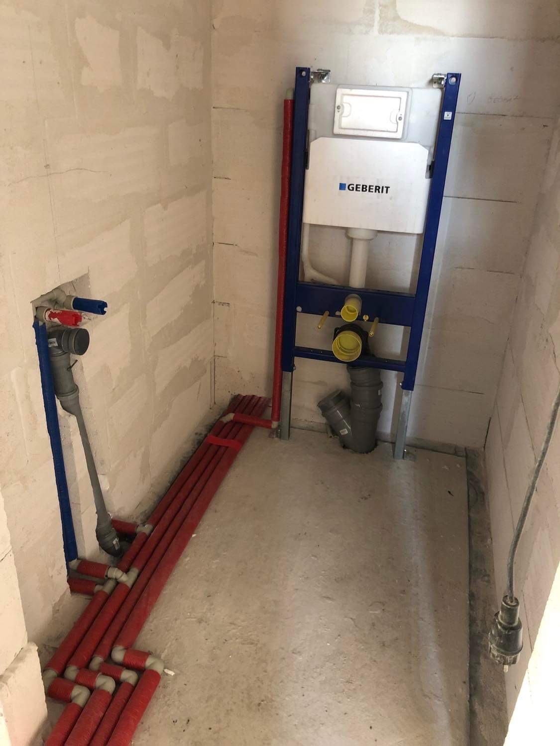 Surowy stan łazienki z zamontowanym stelażem podtynkowym Geberit, widoczne rury instalacji wodnej i kanalizacyjnej, ściany w stanie deweloperskim.