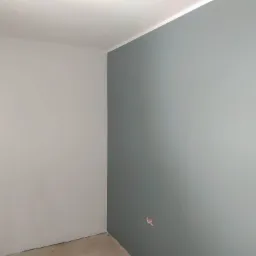 Świeżo pomalowane ściany w Tarnowie, jedna w odcieniach szarości, druga w delikatnym błękicie, widoczne puszki po gniazdkach elektrycznych.