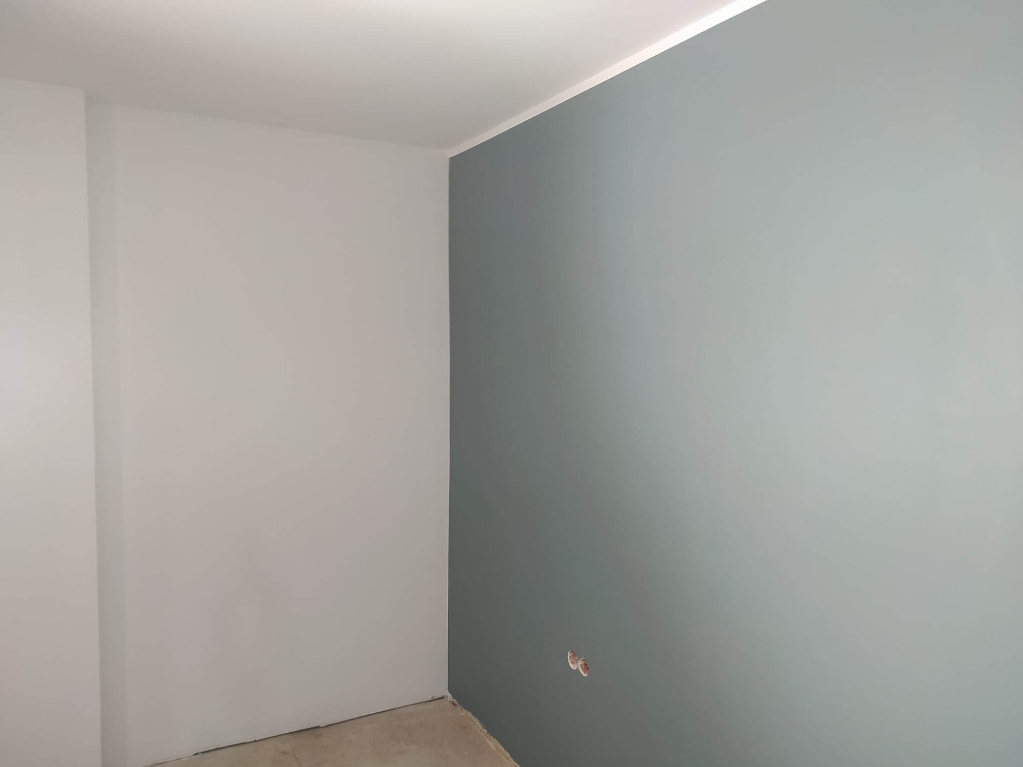 Świeżo pomalowane ściany w Tarnowie, jedna w odcieniach szarości, druga w delikatnym błękicie, widoczne puszki po gniazdkach elektrycznych.