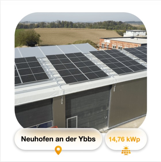 Instalacja paneli słonecznych na dachu budynku przemysłowego, widok z góry, w tle pola i zabudowania.