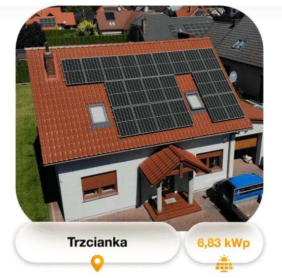 Dom jednorodzinny z czerwoną dachówką w Trzciance, na dachu panele fotowoltaiczne zamontowane nad oknami dachowymi, widoczny samochód dostawczy.