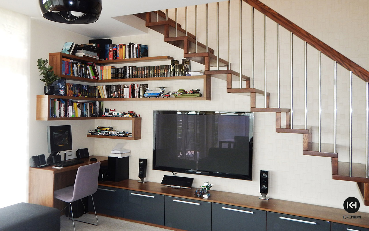 Nowoczesny salon z drewnianymi, wiszącymi półkami na książki i kolekcje, schodami z drewnianymi stopniami i metalowymi poręczami, oraz szafką RTV z szarymi frontami i długimi, poziomymi uchwytami.