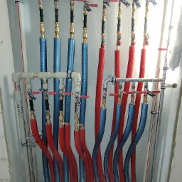 Rozdzielacz instalacji CO i CWU z rurami w izolacji, zamontowany w nowym budownictwie w Krakowie. Widoczne zawory i precyzyjne połączenia.