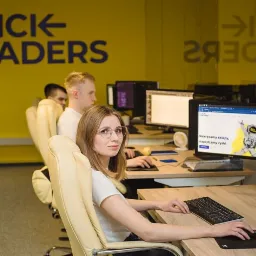 Zespół Click Leaders pracuje nad stroną internetową z motywem kosmicznym w biurze z żółtą ścianą i logo firmy.