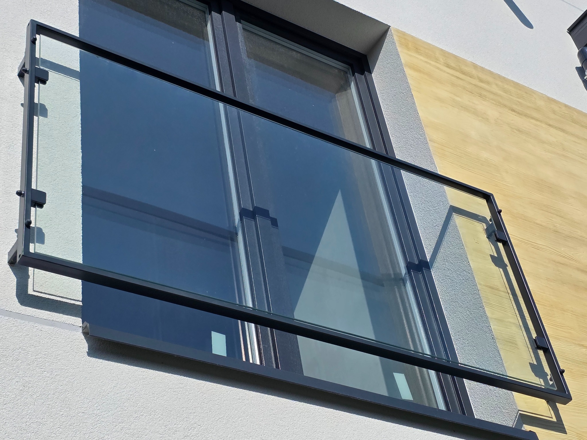 Nowoczesna balustrada szklana z czarną ramą, zamontowana na balkonie w Halinowie. Minimalistyczny design, widok z dołu, jasne oświetlenie.