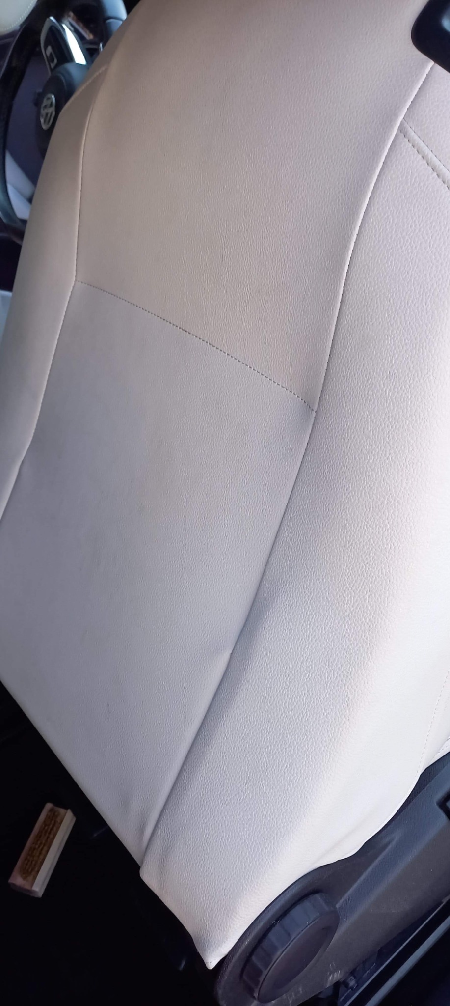 Jasny, skórzany fotel samochodowy z widocznym szwem i elementami regulacji, czyszczony szczotką z włosiem.