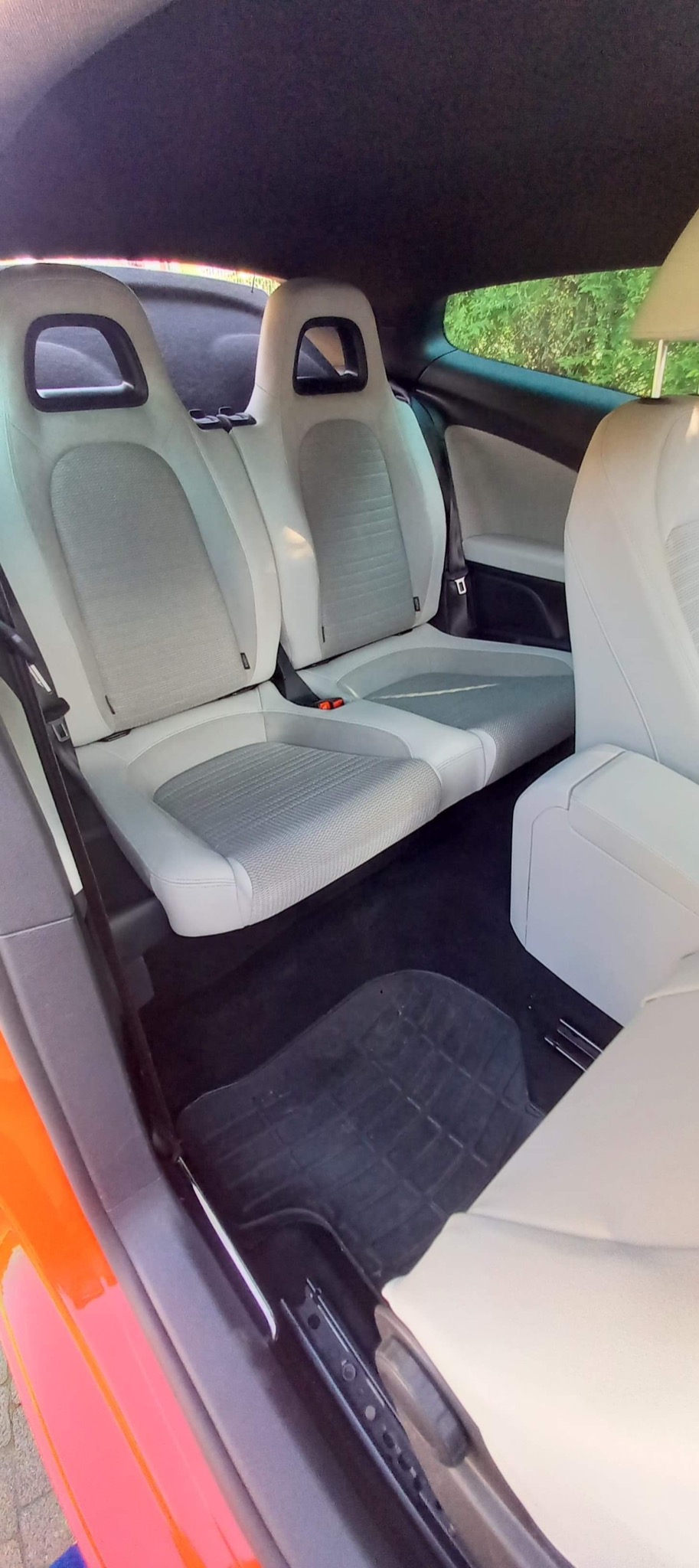 Wnętrze samochodu z jasną tapicerką po gruntownym czyszczeniu, widoczne odkurzone dywaniki i wyczyszczone fotele z elementami szarej tkaniny.