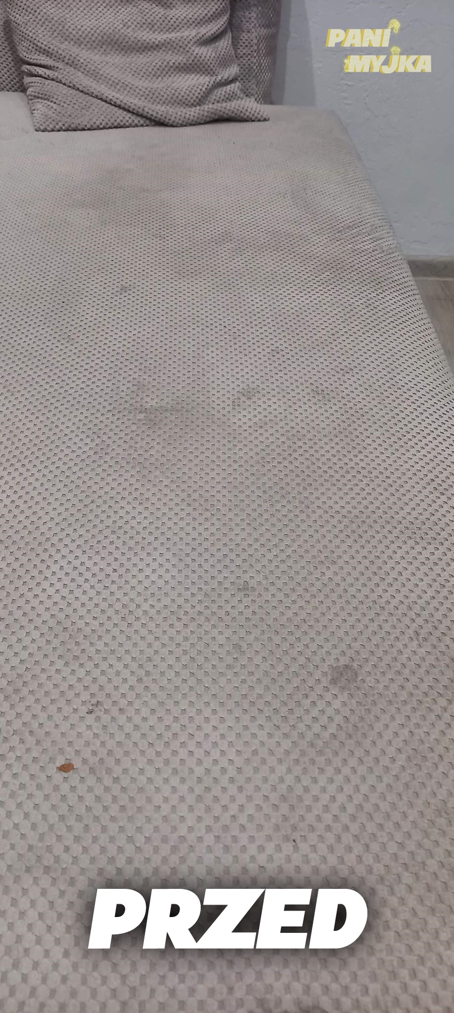 Brudna tapicerka sofy z plamami, widok 'przed' czyszczeniem w Jastrzębiu-Zdroju, z widocznym logo firmy sprzątającej w rogu.