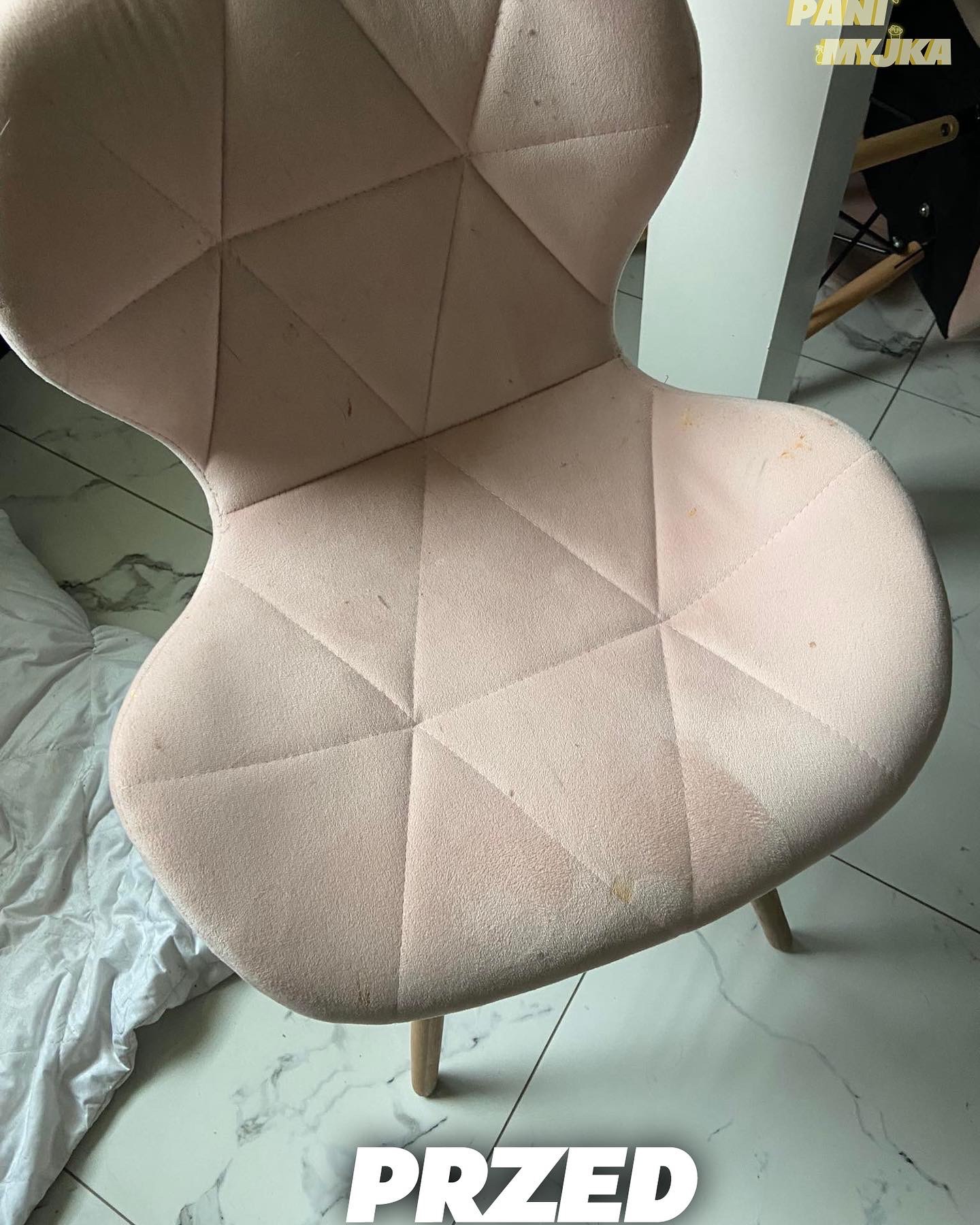 Różowe, tapicerowane krzesło z geometrycznym wzorem przed czyszczeniem, widoczne plamy i zabrudzenia na siedzisku i oparciu, na tle marmurowej podłogi.
