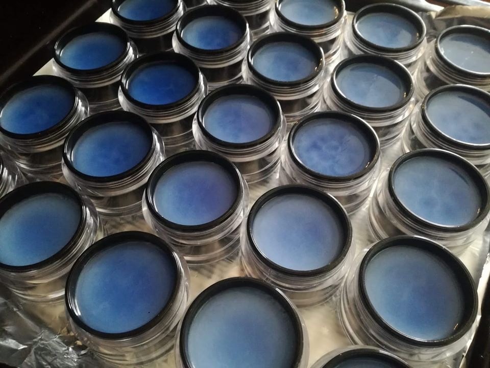 Wiele przezroczystych słoiczków z granatowym żelem na folii aluminiowej, widoczne delikatne smugi i różnice w odcieniach w każdym słoiczku.