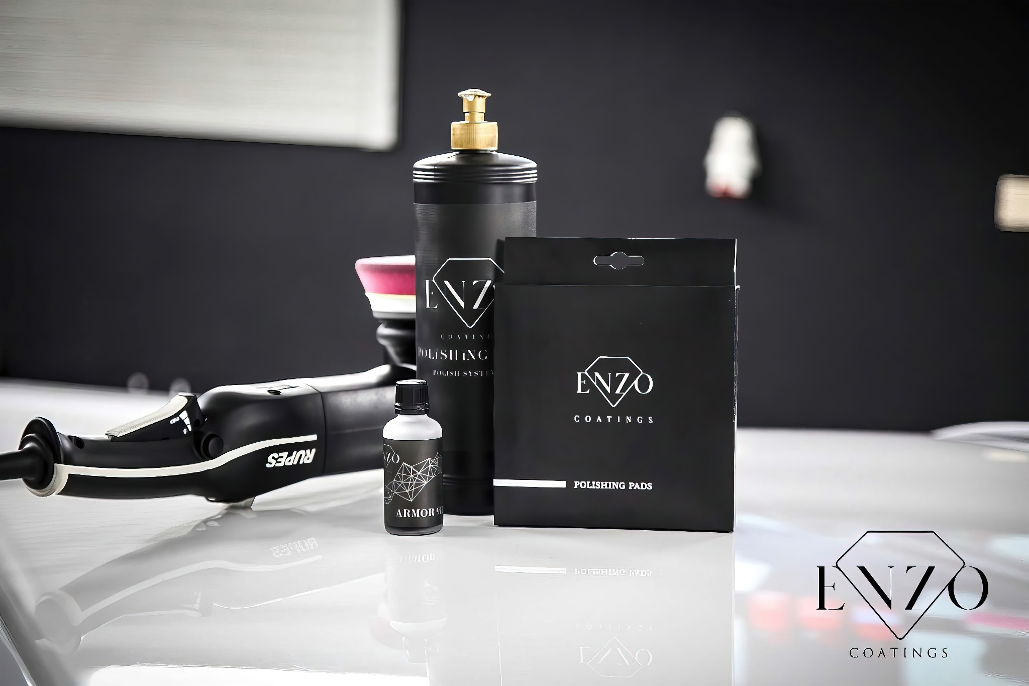 Zestaw produktów do polerowania lakieru samochodowego marki Enzo Coatings, w skład którego wchodzi polerka Rupes, pasta polerska, płyn ochronny Armor 90 i pady polerskie, wszystko na błyszczącym...