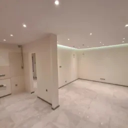 Jasne, przestronne wnętrze po remoncie z marmurową podłogą, nowymi gładziami na ścianach, oświetleniem punktowym w suficie i minimalistycznymi lampami wiszącymi.