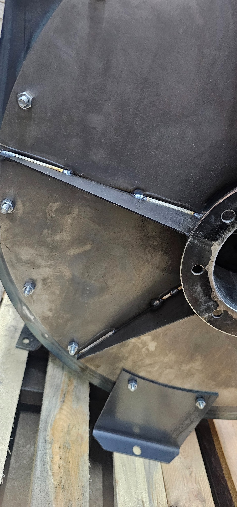 Szczegółowe ujęcie metalowej konstrukcji wentylatora przemysłowego z widocznymi spawami i śrubami mocującymi, umieszczonej na palecie.