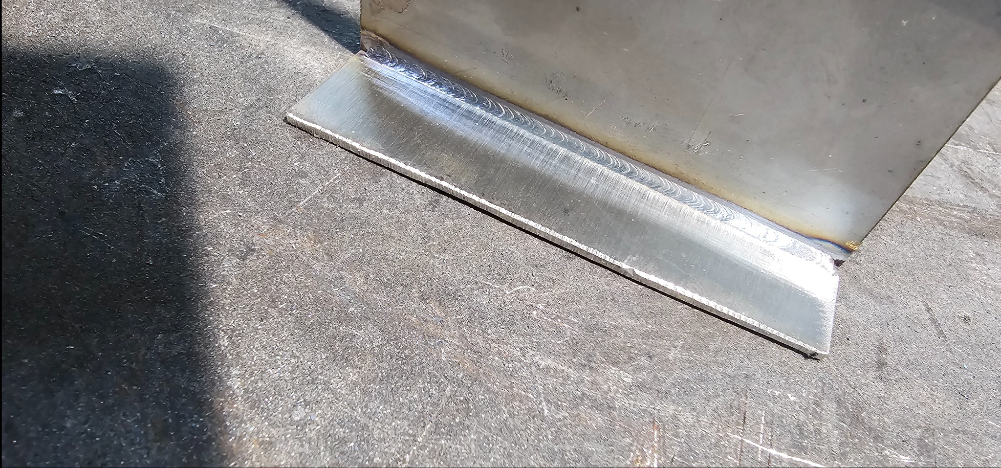 Spoina pachwinowa łącząca dwie metalowe płyty pod kątem prostym, widoczne ślady obróbki i minimalne przebarwienia termiczne na spoinie.