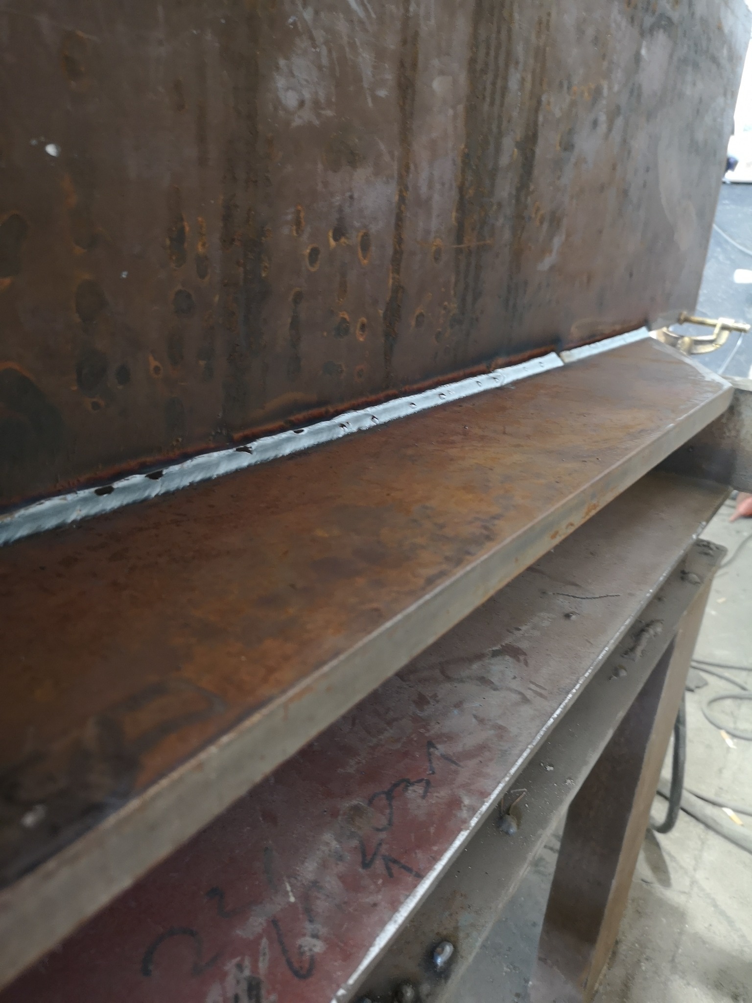 Metalowa konstrukcja z widocznym świeżym spawem, rdzawe powierzchnie, niedoskonałości spoiny.