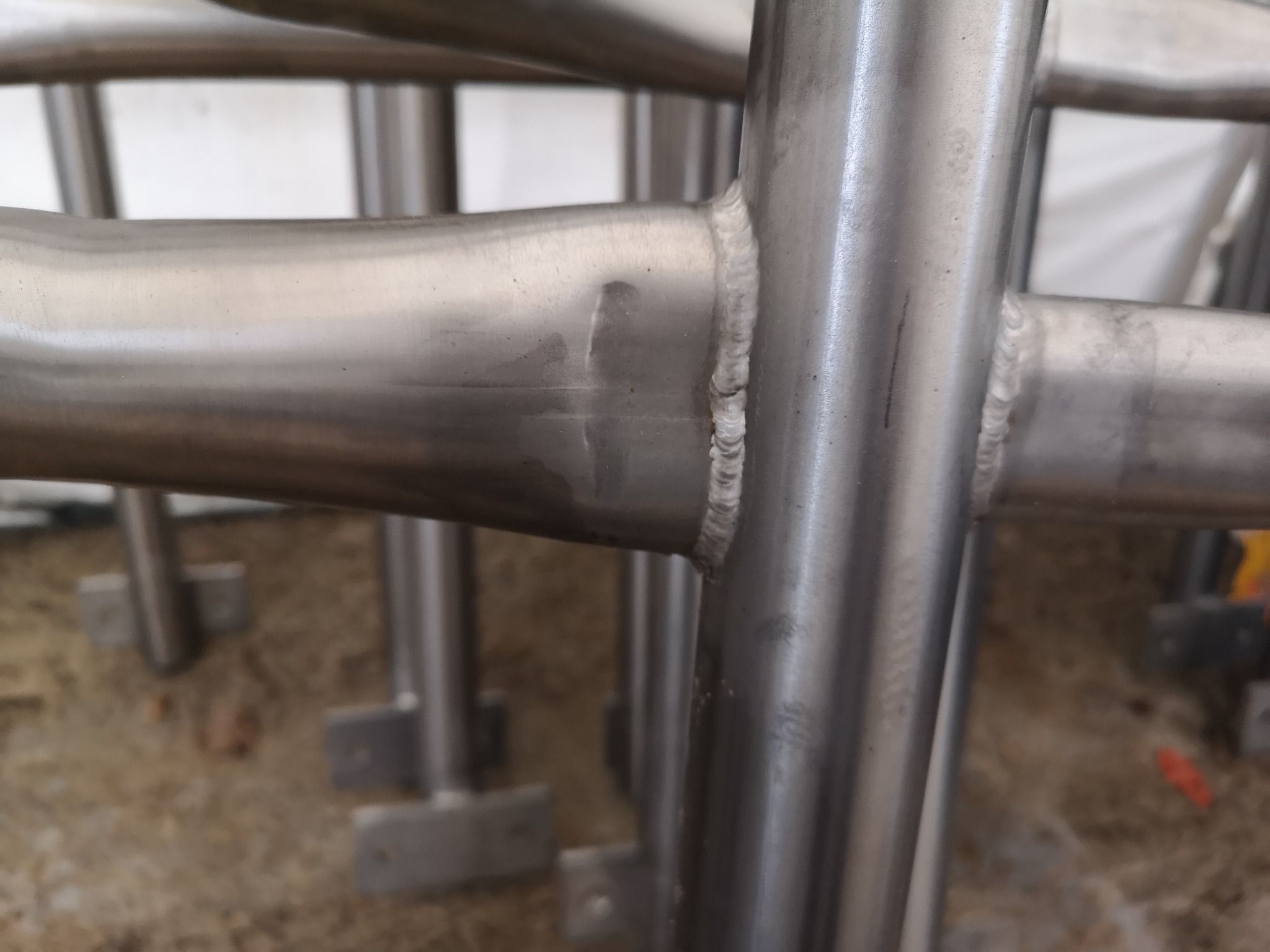 Szczegółowe ujęcie spawu na ramie z rur stalowych, widoczne ślady obróbki i nierówności spoiny.