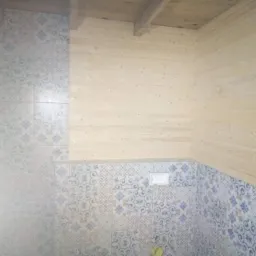 Wykończona łazienka z drewnianą boazerią i dekoracyjnymi płytkami w odcieniach błękitu i szarości, sufit wykończony drewnem.