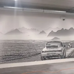Czarno-biały druk wielkoformatowy na ścianie przedstawiający Porsche Carrera 4 na tle górskiego krajobrazu z drogą