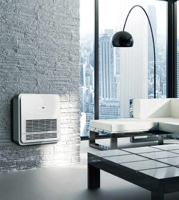 Biały klimatyzator ścienny z widocznymi żaluzjami w nowoczesnym wnętrzu z ceglaną ścianą, panoramicznym oknem z widokiem na miasto i designerską lampą łukową.