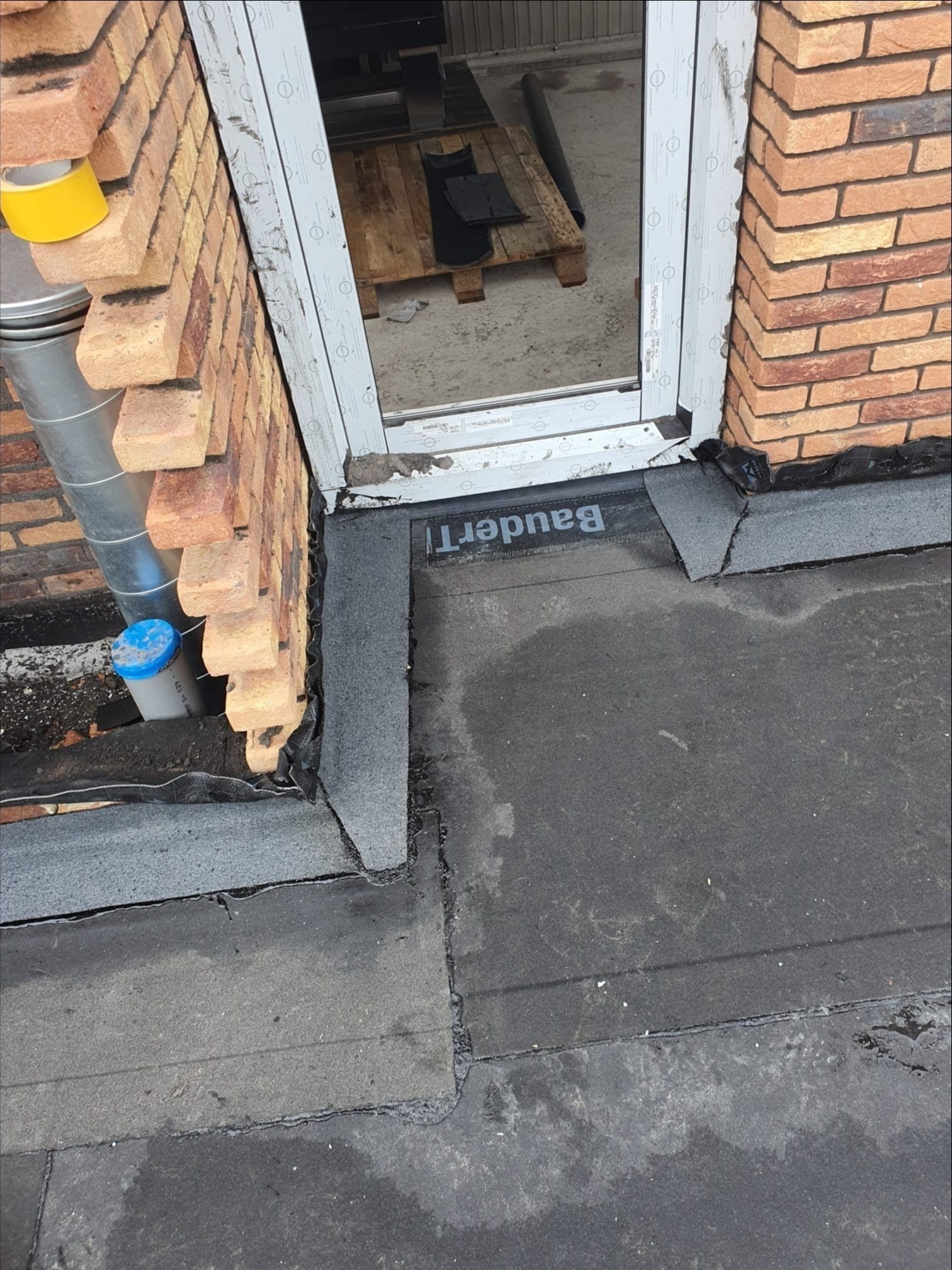 Połączenie nowego okna z murem z cegły i hydroizolacją dachu z papy marki BauderT.