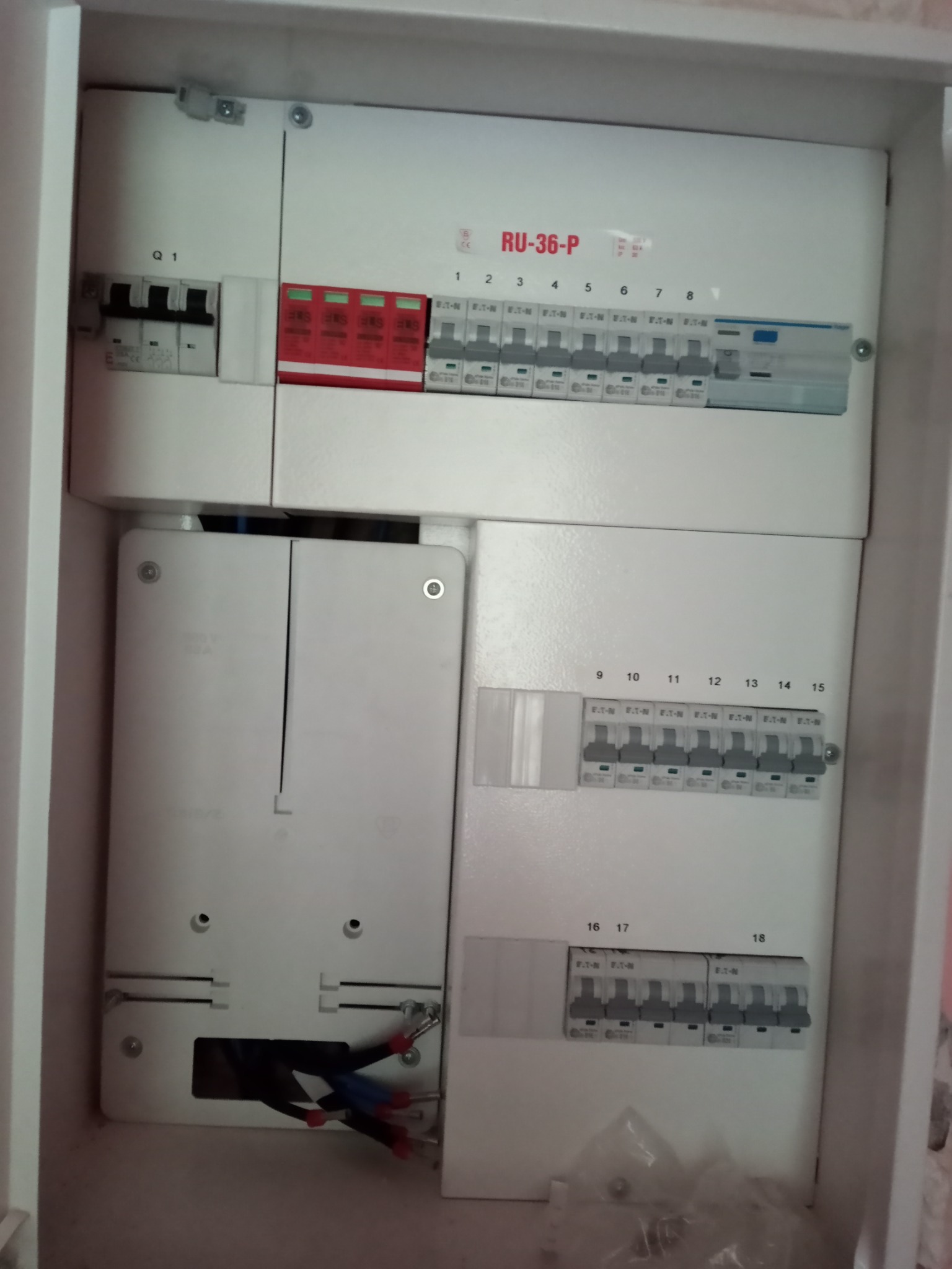 Rozdzielnica elektryczna z zainstalowanymi bezpiecznikami i przewodami, widok z bliska na wnętrze szafki z numeracją obwodów.