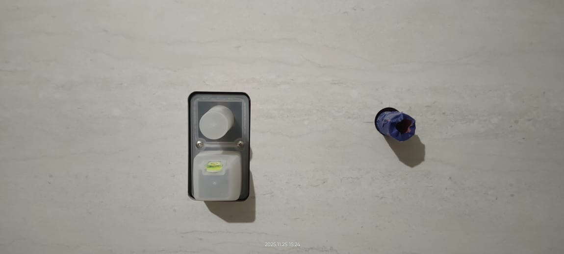 Szara ściana z zamontowanym podtynkowym zestawem wodno-kanalizacyjnym z poziomicą i zaślepką oraz niebieską rurą w ścianie. Instalacja wodno-kanalizacyjna.