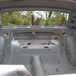 Stardust - Wnętrze karoserii auta po piaskowaniu i zabezpieczeniu antykorozyjnym, widoczne otwory i wzmocnienia. Tło stanowi zieleń drzew.