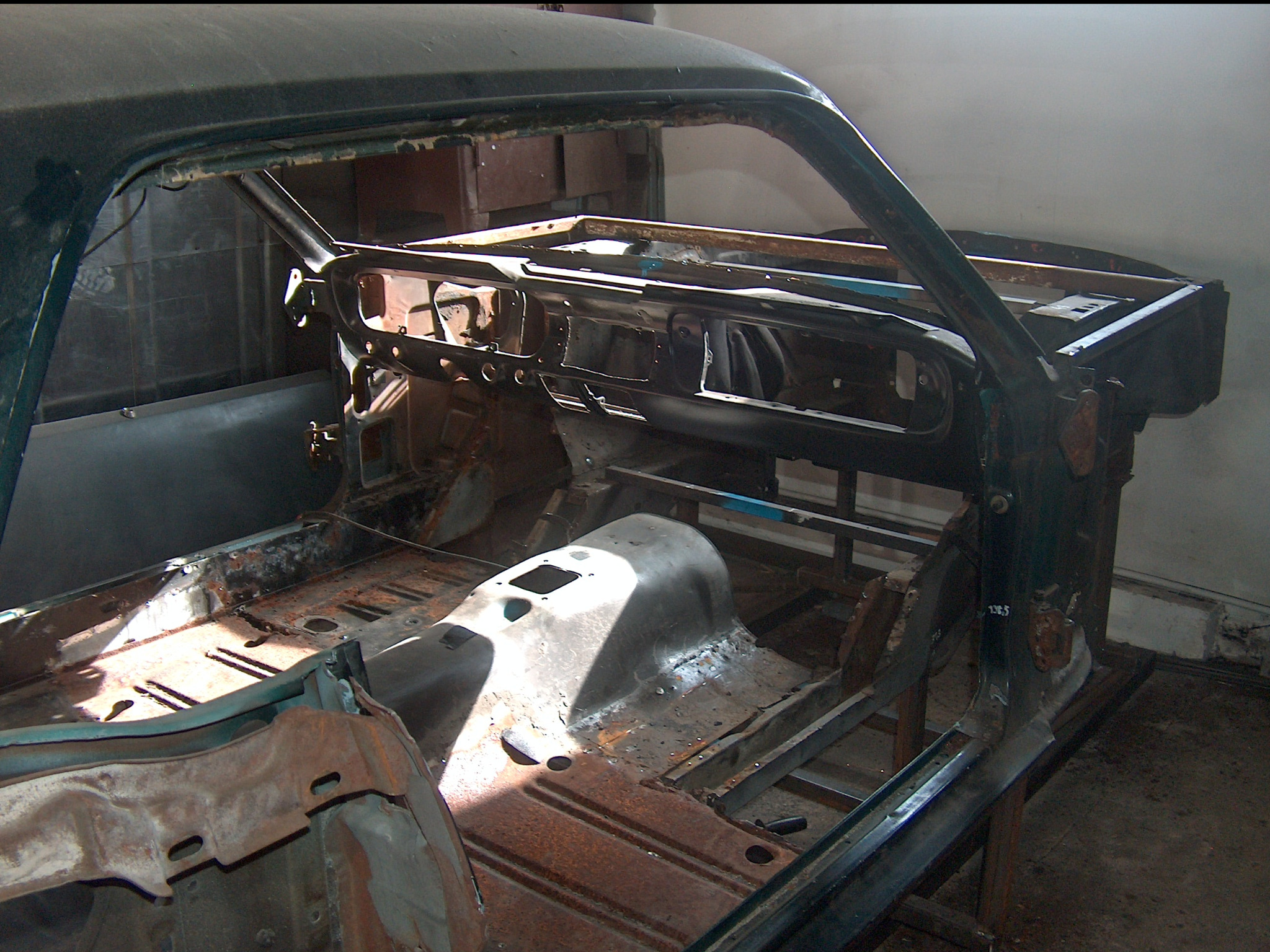 Wnętrze odrestaurowywanego, klasycznego samochodu. Widoczne elementy karoserii w trakcie prac blacharskich, z rdzawym nalotem i śladami spawania.