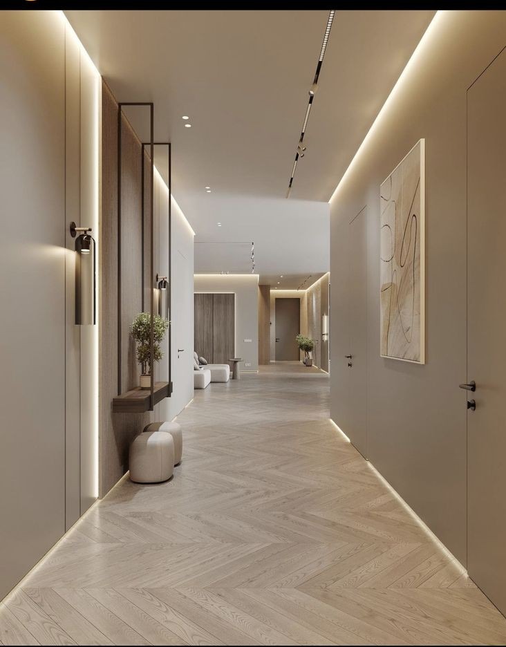 Nowoczesny korytarz z parkietem ułożonym we wzór jodełki, oświetleniem LED wzdłuż ścian i sufitu, minimalistycznymi meblami i dekoracjami roślinnymi.