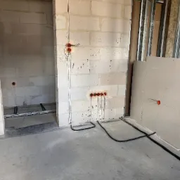 Surowy stan: instalacja elektryczna w ścianach z betonu komórkowego i rurki pod podłogą, widoczne profile do płyt gipsowych. Wnętrze w trakcie prac wykończeniowych.