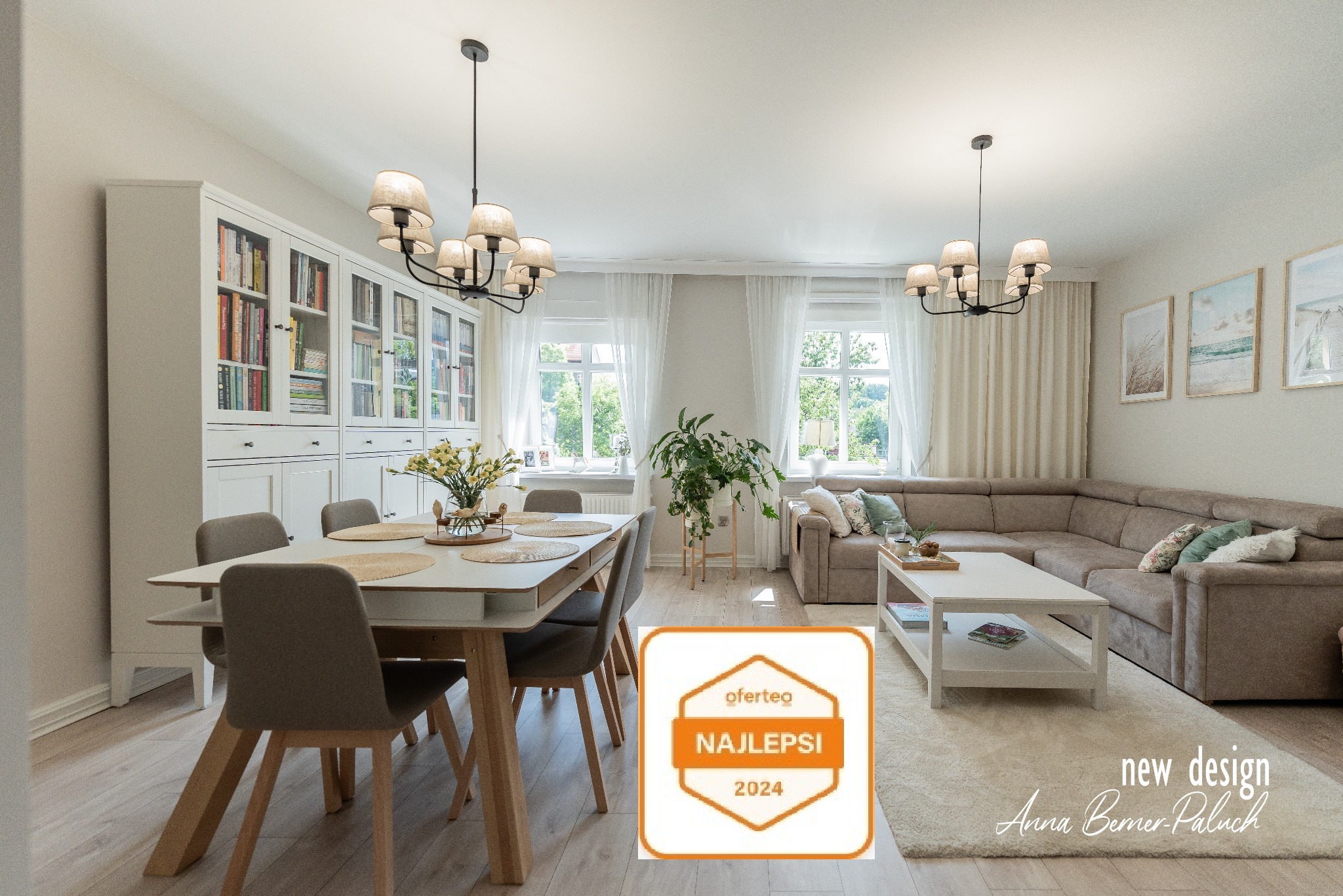 Jasne, przestronne wnętrze salonu z jadalnią: stół z szarymi krzesłami, duży narożnik, biała biblioteczka i wiszące lampy w stylu industrialnym.