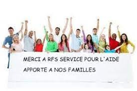 Grupa uśmiechniętych osób, w tym dzieci, stojąca za białym transparentem z napisem 'MERCI A RFS SERVICE POUR L'AIDE APPORTE A NOS FAMILLES', wszyscy z podniesionymi rękami w geście radości...