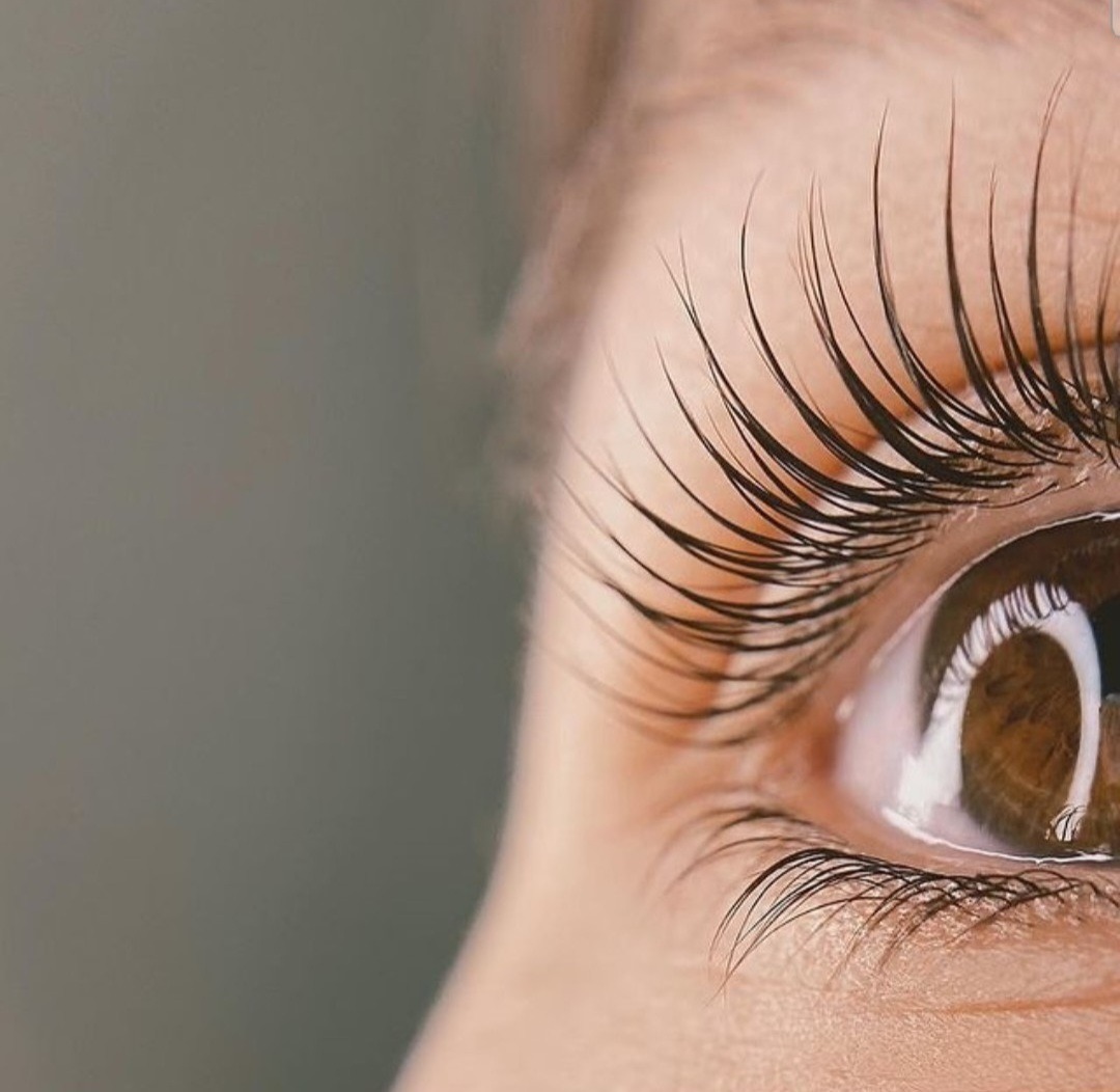 Zbliżenie na oko z długimi, gęstymi, profesjonalnie przedłużonymi rzęsami, widoczne brązowe tęczówka i dolna powieka.