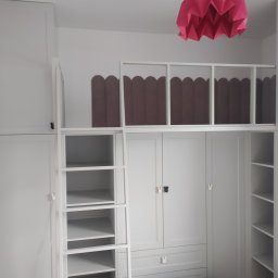 Remonty Wykończenia Wnętrz Michał Krajewski - Biała zabudowa meblowa z antresolą i drabinką w pokoju dziecięcym, różowy, origami-stylizowany abażur lampy sufitowej.