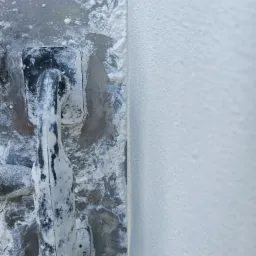 Gładź nałożona na ścianę, widoczna paca z resztkami gładzi, zbliżenie na strukturę ściany.