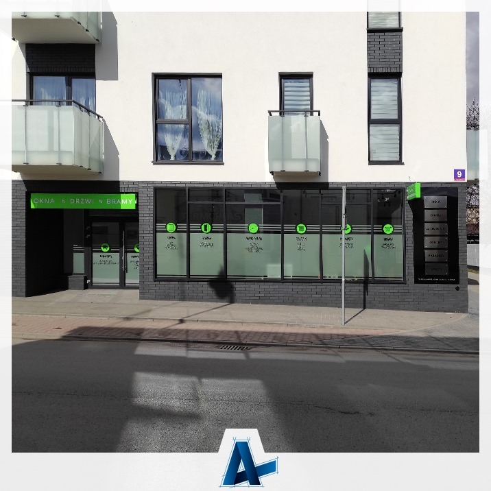 Fasada budynku z oknami PCV, drzwiami i roletami zewnętrznymi, z widocznym szyldem firmy oferującej te usługi.